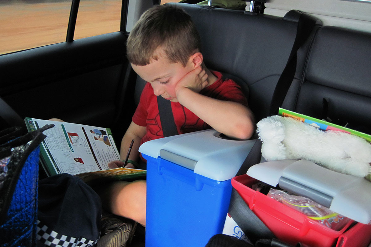 boy doing activities in the back of the car