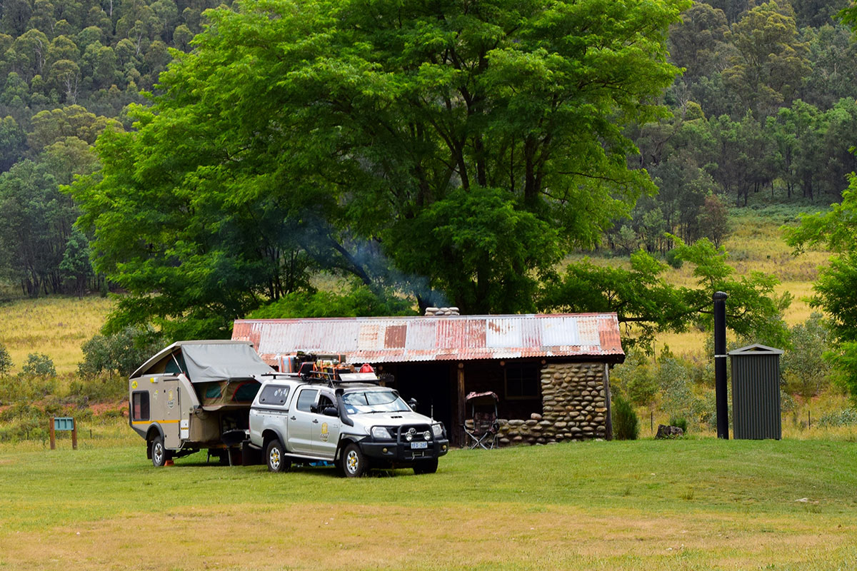 4WD towing a camper trailer parked outside a cottage in the high country