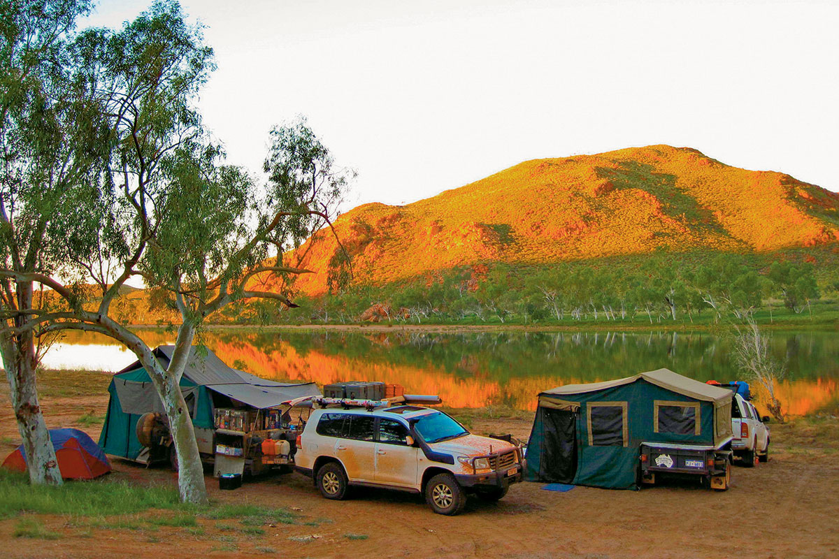 A campsite with two parked 4WD with tents and a mountain back drop